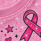 Close-up of the printed sparkle texture and pink ribbon artwork on the t-shirt fabric