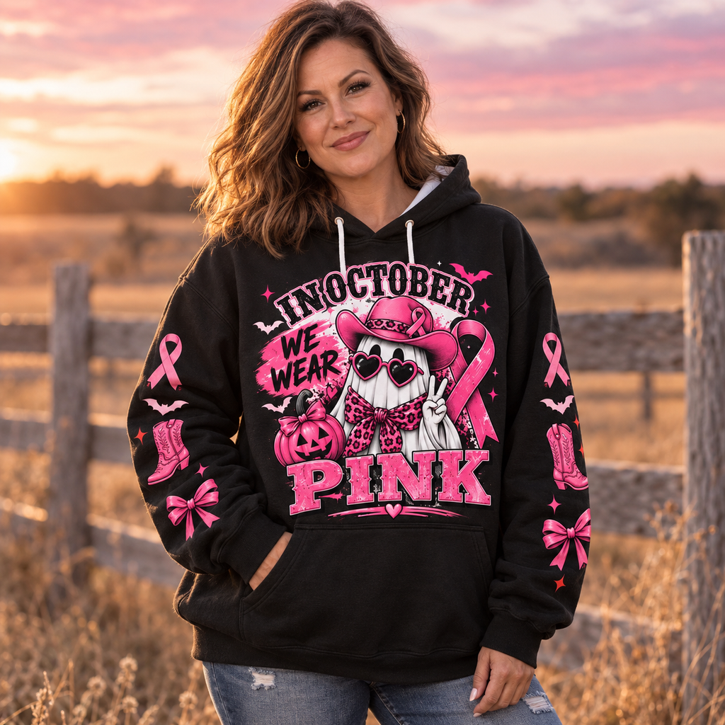 Woman wearing the In October We Wear Pink hoodie in a field at sunset